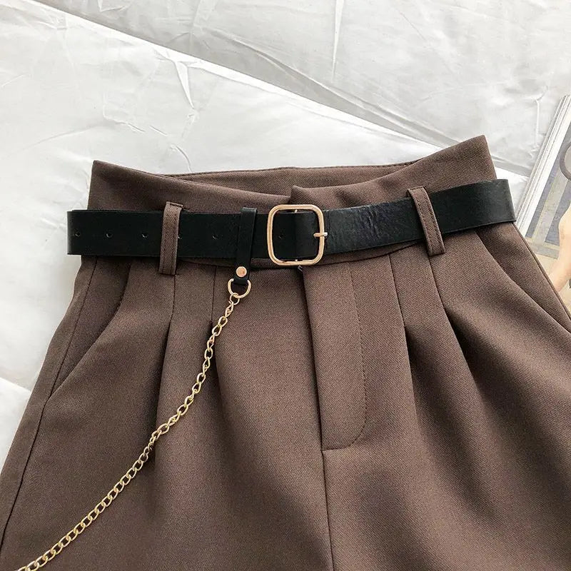 Brown pants with a black belt and gold chain on a light gray background