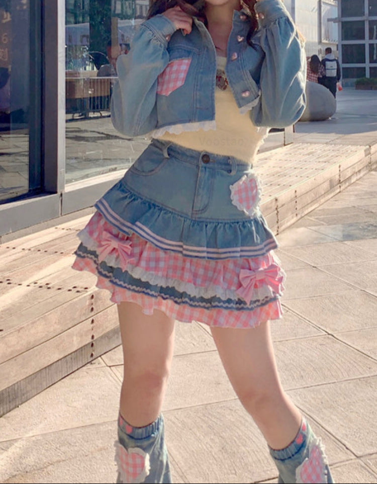 Person wearing a denim jacket and skirt with a checkered pattern on a city street.