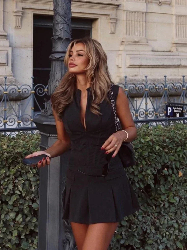 Woman in a black dress standing outdoors with a building in the background