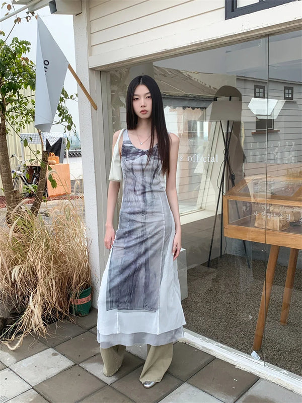 Woman standing outside a building with a glass door, wearing a patterned dress.