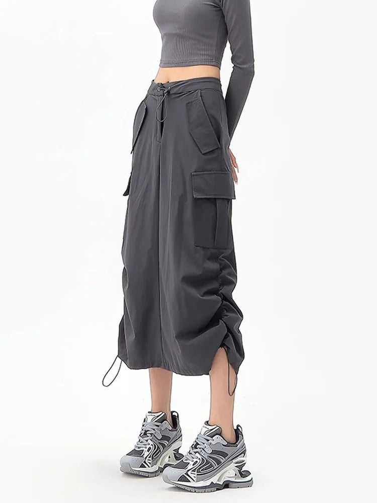 Person wearing a gray crop top and cargo pants with a white background