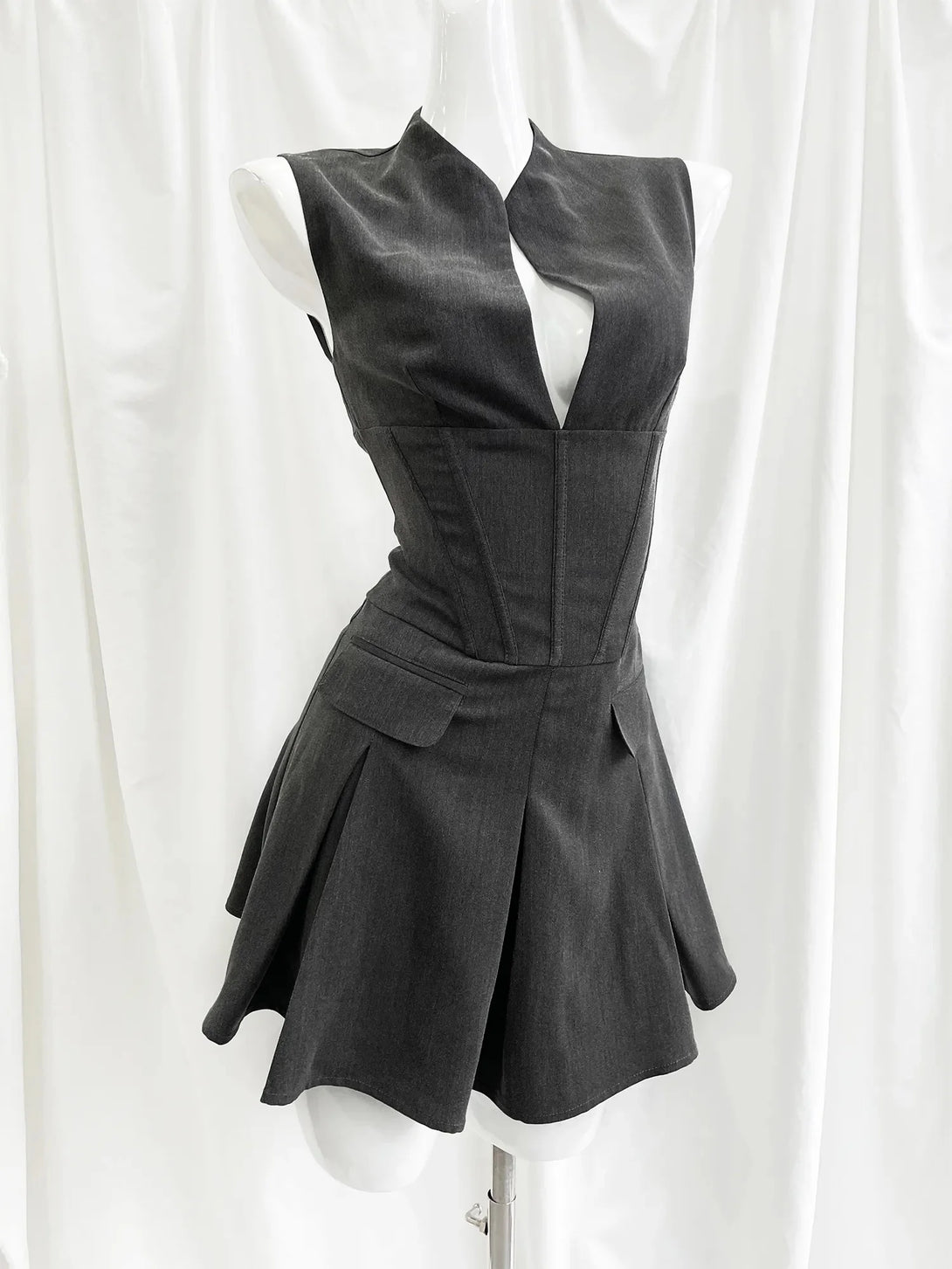 Black sleeveless dress on a mannequin against a white curtain background