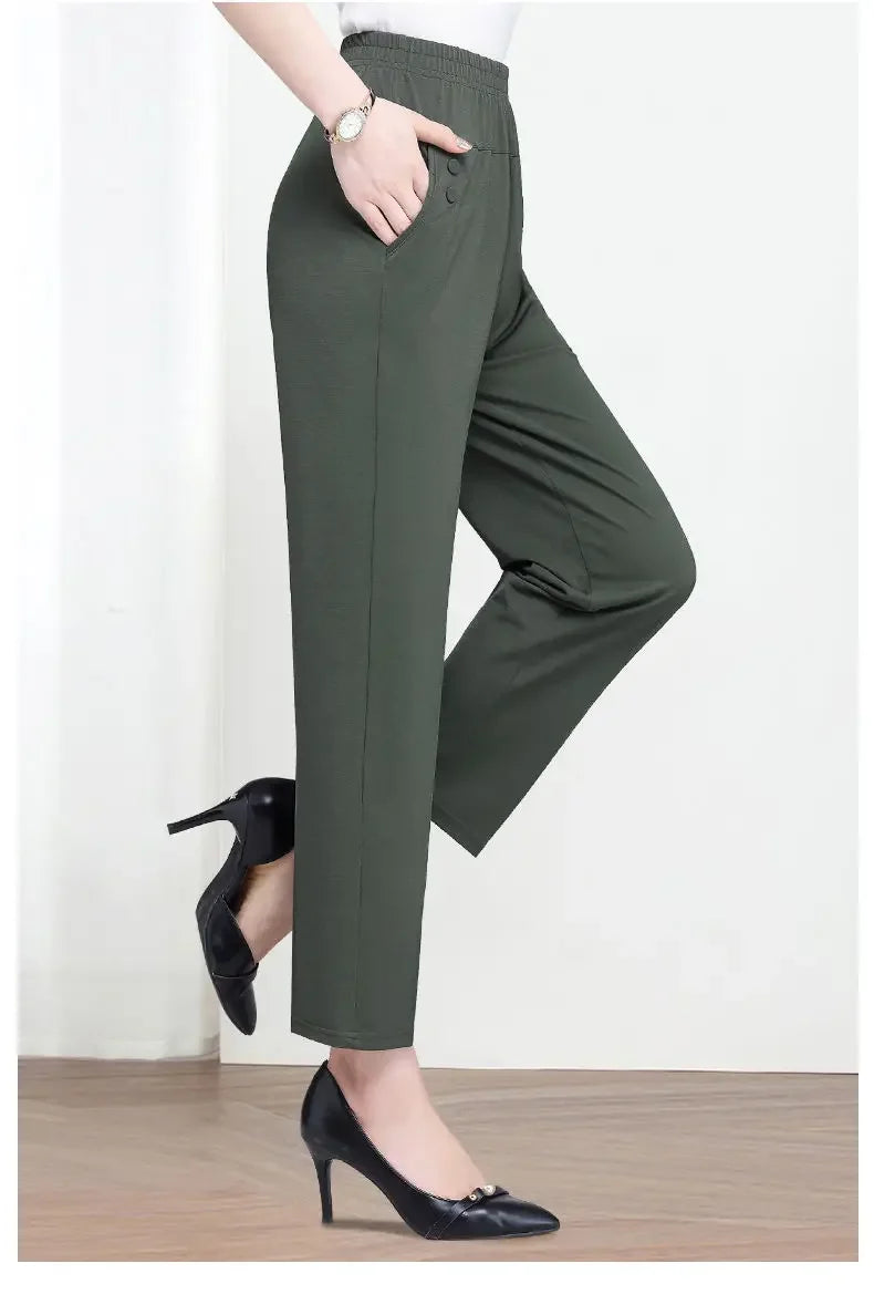 Person wearing green pants and black high heels on a white background