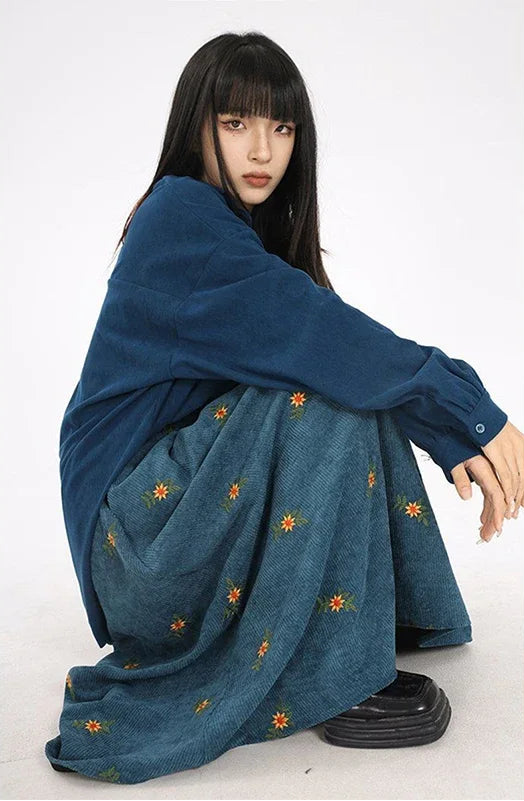 Person wearing a blue dress with floral embroidery on a white background