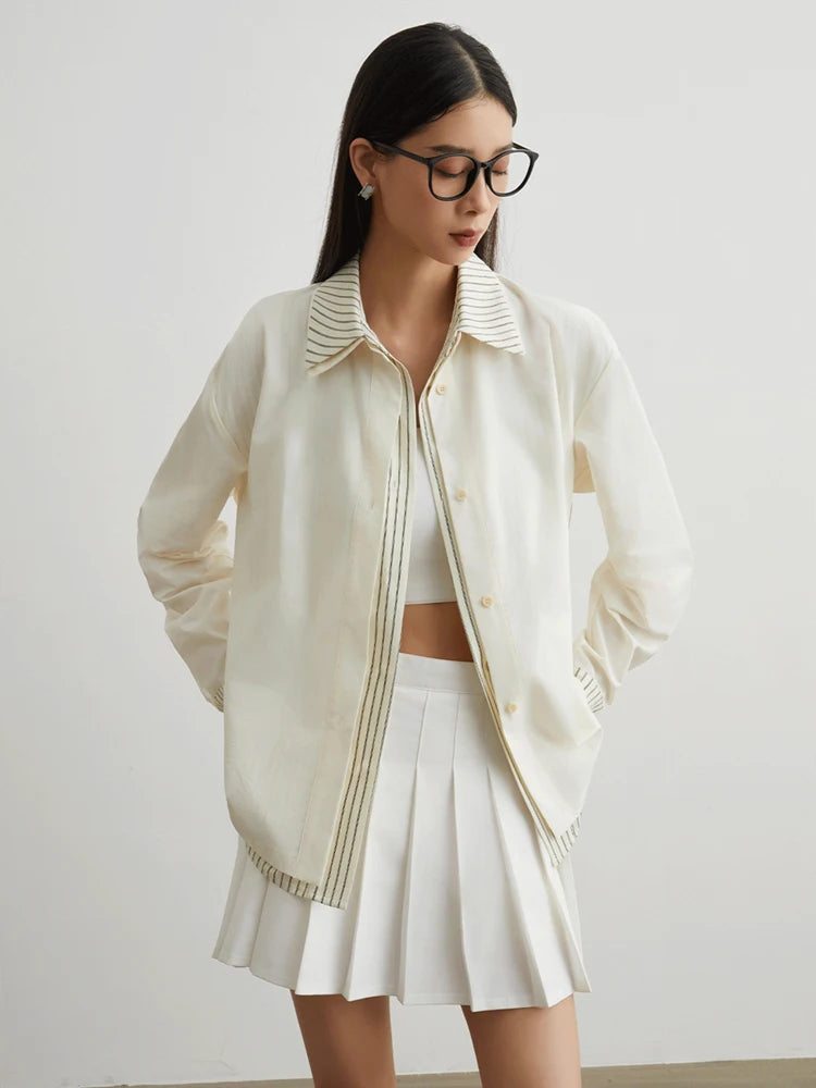 Woman wearing a cream-colored jacket and skirt with a white background
