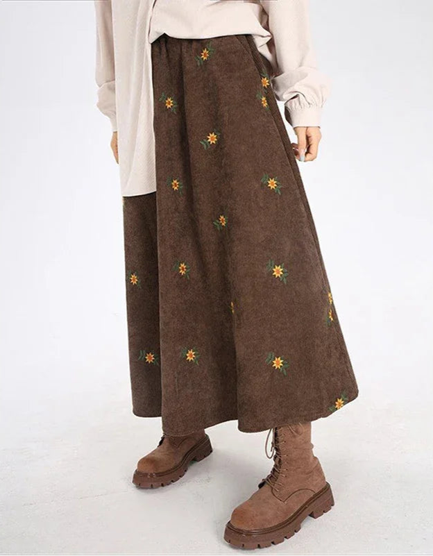Brown skirt with floral embroidery worn by a person on a white background