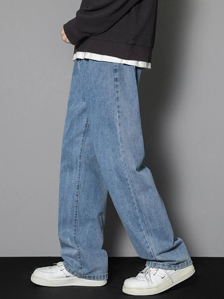 Person wearing blue jeans and white sneakers on a gray background