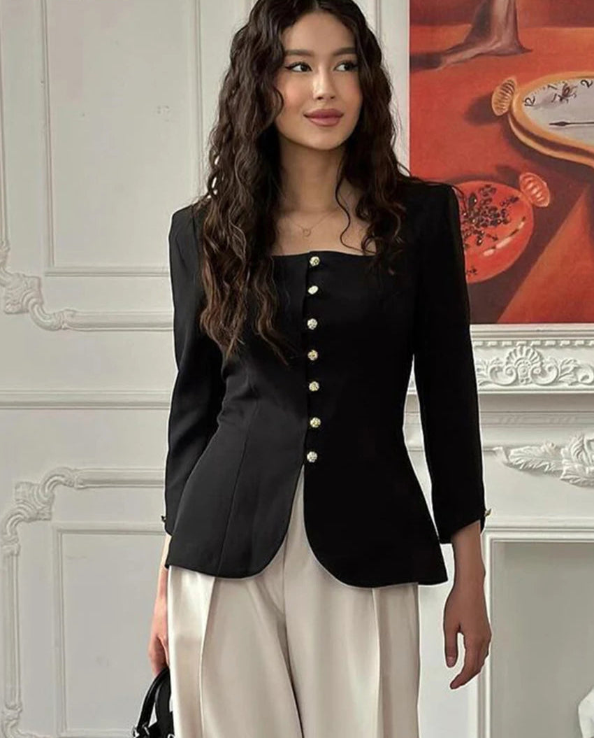 Woman wearing a black blazer with white buttons in an elegant interior setting